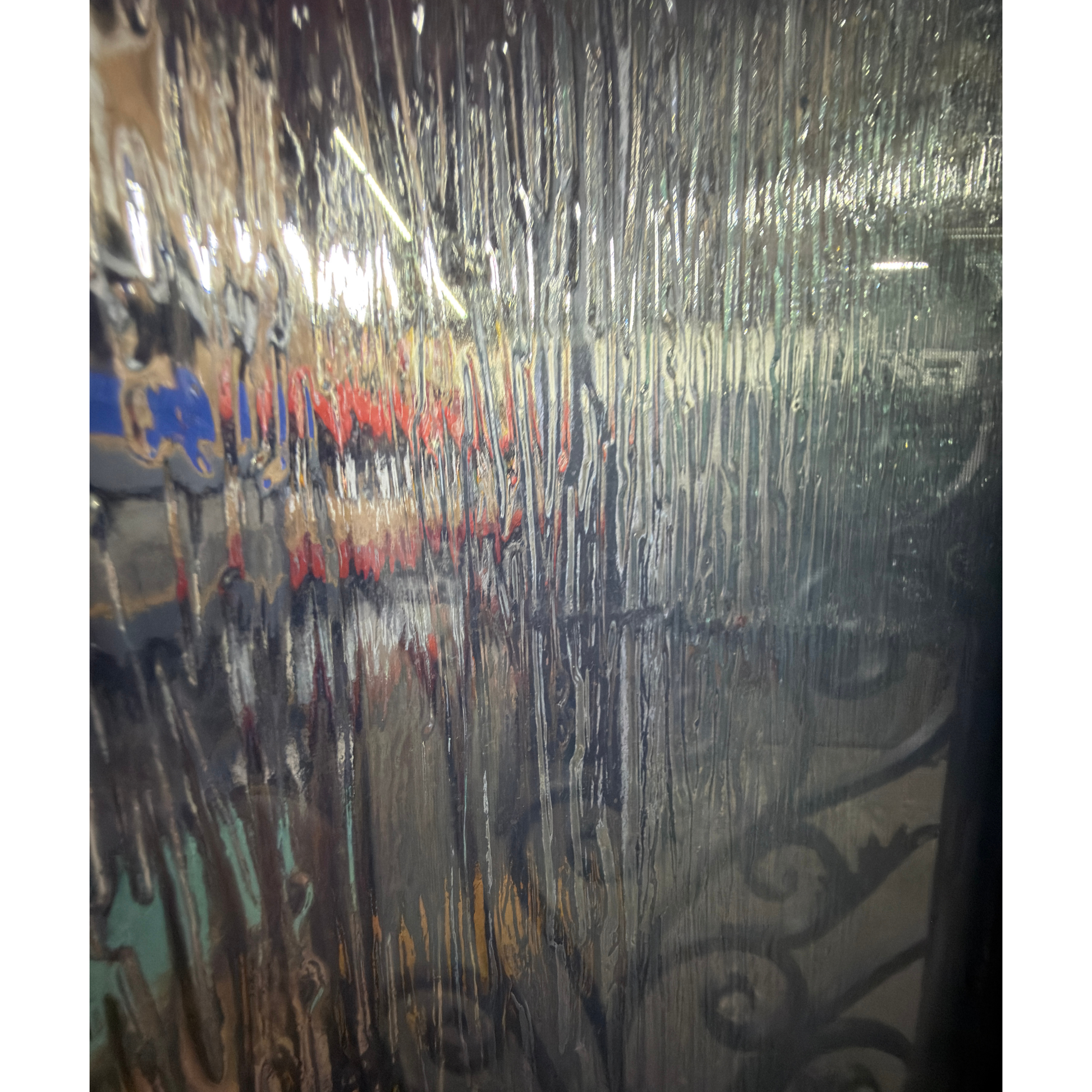 Black wrought iron door with decorative glass panel on a beige wall.