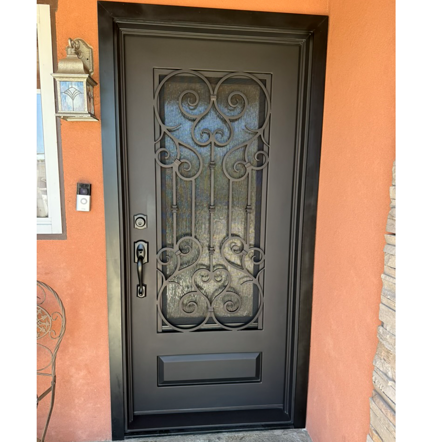 Decorative black wrought iron door on a peach-colored wall