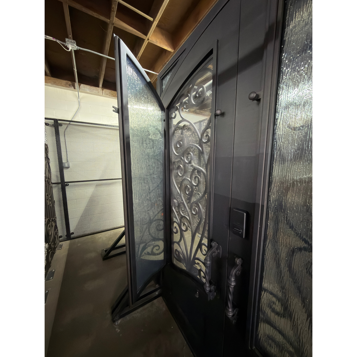 Black wrought iron double door with decorative glass panels on a beige wall.